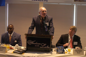 Ed Ingles speaking at a Hauppauge Industrial Association (HIA) event. To his left is Michael Coleman, a Channel 12 sportscaster. To his right his Frank Boulton, CEO of the Long Island Ducks baseball team.