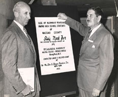 Chappell standing by a poster exemplifying his Alcoholic study of Nassau County