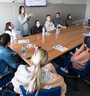 Students sitting around a conference table while professor is teaching