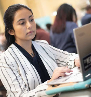 Female student in business attire on laptop
