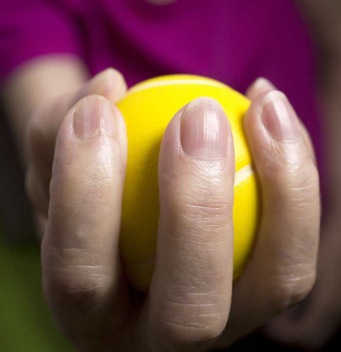 A hand squeezing a tennis ball