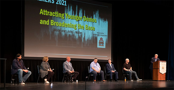 WRHU Radio operations director John T. Mullen (right) moderates the “Attracting Younger Demos and Broadening the Base” panel at TALKERS 2021 at Hofstra University on Friday, June 11. Panelists were (from l-r): Derek Hunter, talk host WCBM, Baltimore; Martha Zoller, talk host WDUN, Gainesville, GA; Sid Rosenberg, morning co-host, WABC, New York; Mike “Bax” Baxendale, morning co-host, WAQY-FM, Springfield,  MA “Rock 102”; Brett Winterble, talk host, WBT-AM/FM, Charlotte; and Dr. Asa Andrew, talk host, Asa Rx.