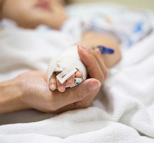 Mother holding baby's hand in hospital