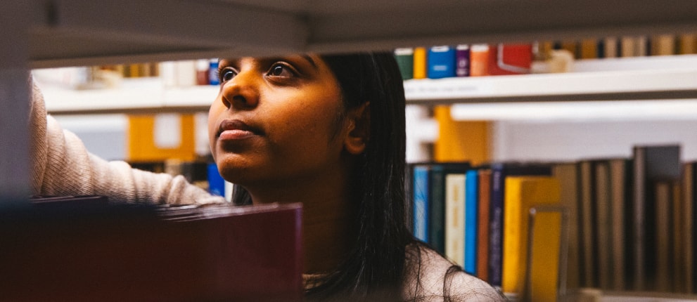 Student in library looking at books