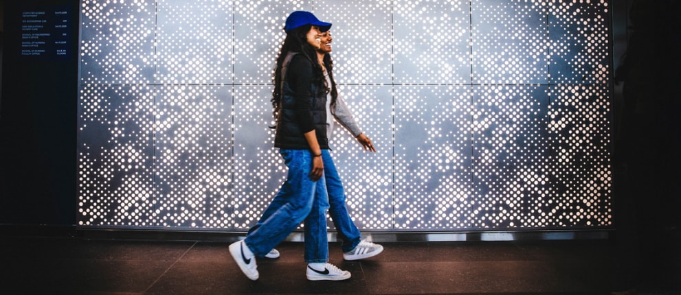 Students walking past a glowing geometric light wall at the Science and Innovation Center