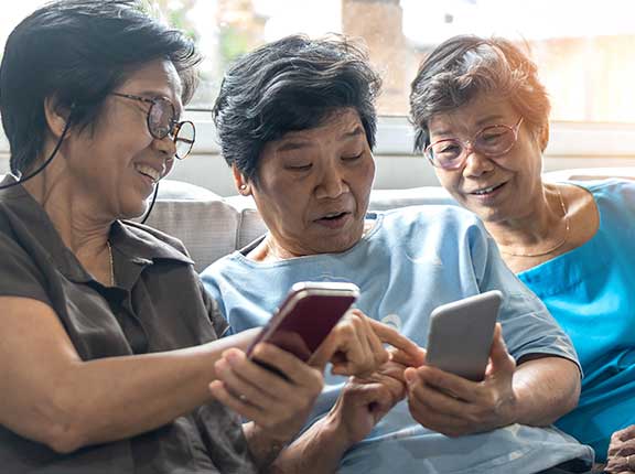 3 elderly Asian ladies looking a a smart phone