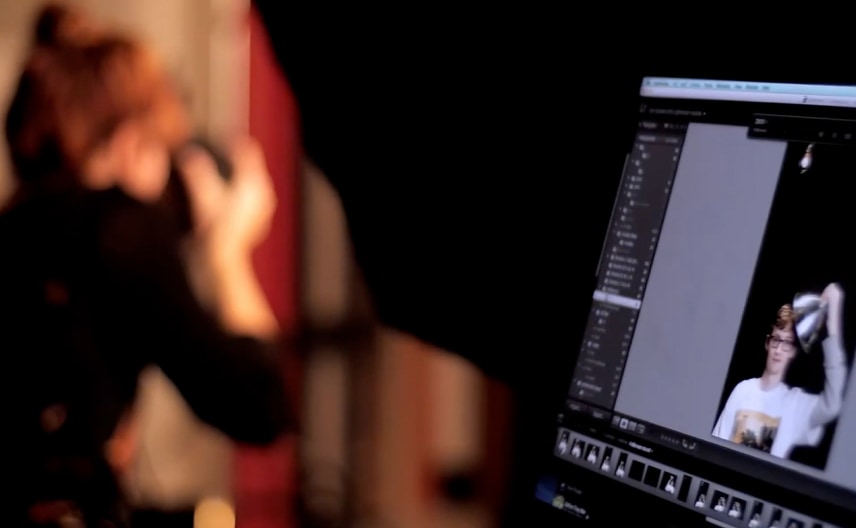 Photography student capturing a studio image while reviewing edits on a computer screen